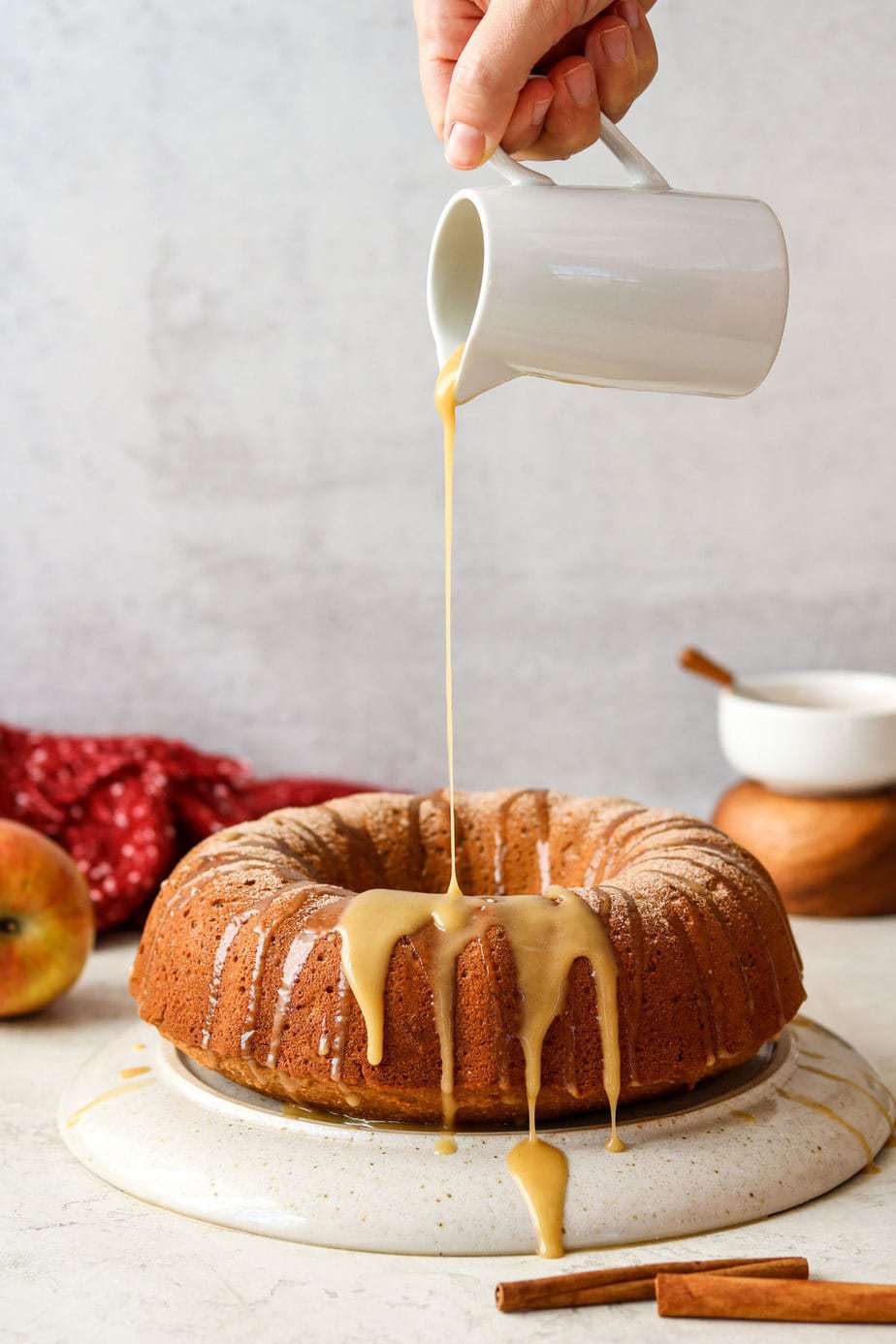 apple cider cake with maple glaze pouring over the top. 